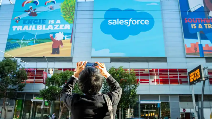Image showing a person taking a picture with their phone of a large Salesforce billboard.