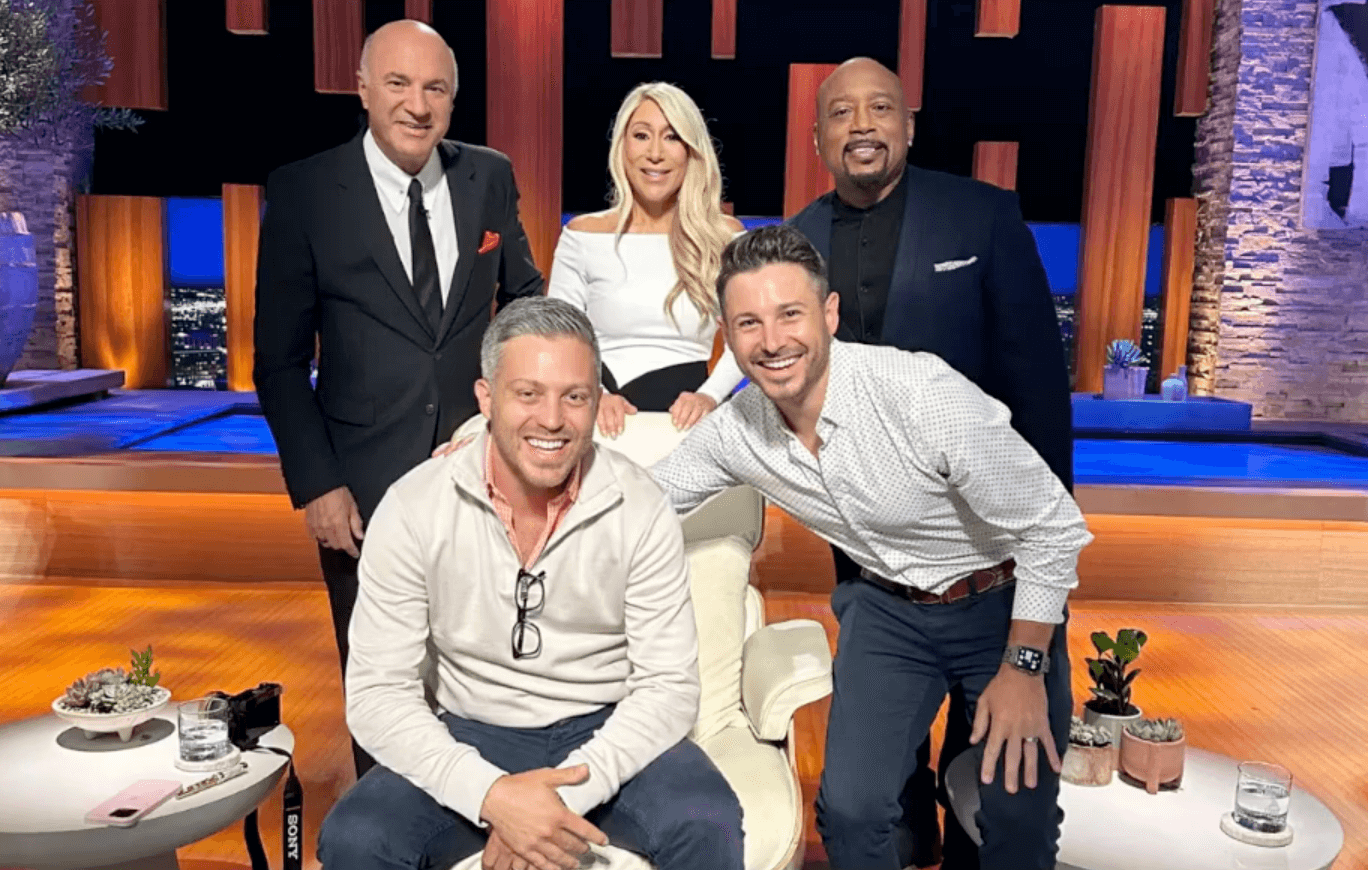 A group photo on the set of Shark Tank featuring Jonathan and Chris Ronzio posing withentrepreneurs posing with Daymond John, Barbara Corcoran, and Kevin O'Leary.